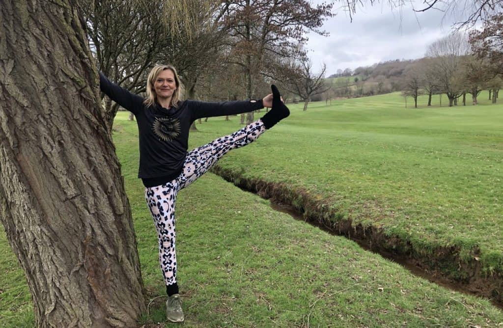 woman standing in tree yoga pose on and Autumn day in the countryside
