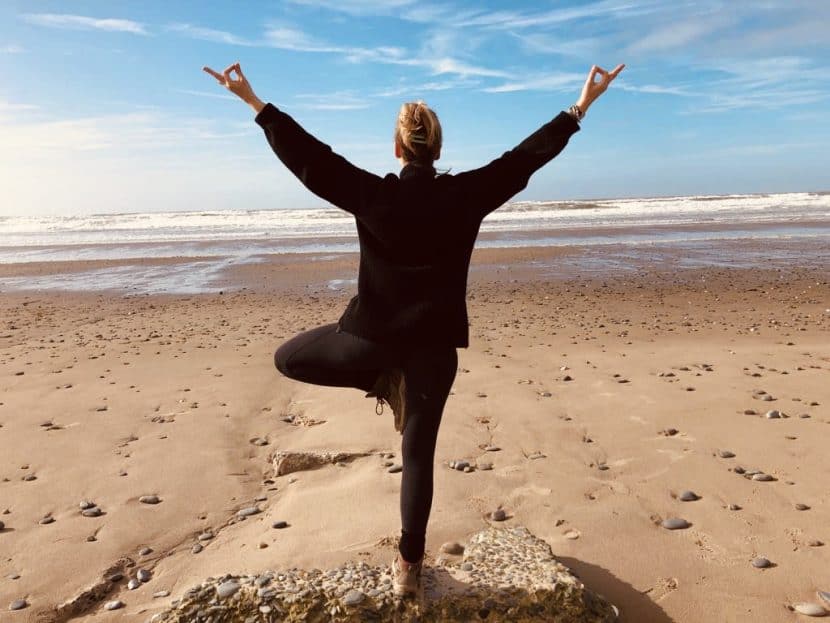 woman standing in tree yoga pose on the beach