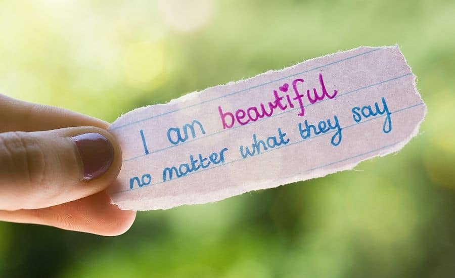 a hand holding written positive affirmations I am beautiful on paper