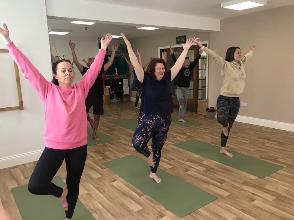 men and women standing in tree pose in a yoga class at shine with Tabitha Yoga in Belper Derbyshire