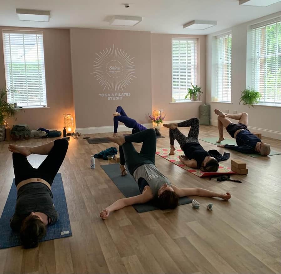 men and women laying in a bridge yoga position in a Vinyasa Yoga class at Shine With Tabitha Yoga in Belper Derbyshire