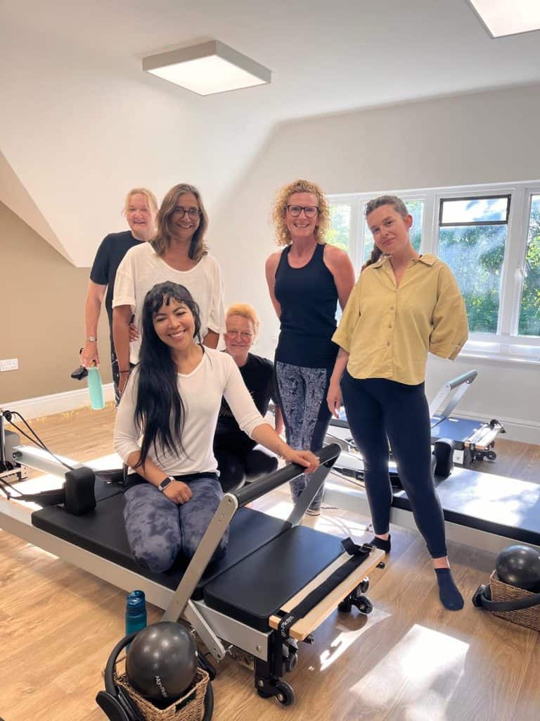 group of ladies standing together in the Shine Reformer Pilates Room after a reformer pilates class